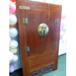 A CHINESE HARDWOOD CUPBOARD, THE DOORS CLOSING ON A CENTRAL CIRCULAR BRASS PLATE AND