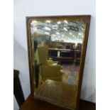 A RECTANGULAR BEVELLED GLASS MIRROR WITHIN A GEORGE III GILT FOLIATE BEZEL AND MAHOGANY FRAME. 65.