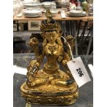 A TIBETAN GILT METAL FIGURE OF THE WHITE TARA SEATED ON A LOTUS THRONE, HER FACE AND HAIR WITH