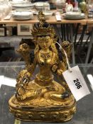 A TIBETAN GILT METAL FIGURE OF THE WHITE TARA SEATED ON A LOTUS THRONE, HER FACE AND HAIR WITH