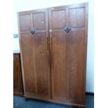 AN ARTS AND CRAFTS OAK WARDROBE, THE DOORS EACH DIVIDED INTO FOUR PANELS, THE DIVISIONS CENTRED