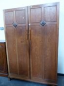 AN ARTS AND CRAFTS OAK WARDROBE, THE DOORS EACH DIVIDED INTO FOUR PANELS, THE DIVISIONS CENTRED