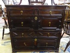 AN 18th C. OAK CHEST OF TWO SHORT AND THREE LONG DRAWERS WITH GEOMETRICALLY PANELLED FRONTS AND ON