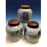A PAIR OF CHINESE BLUE AND WHITE JARS AND WOOD COVERS PAINTED WITH SHOU CHARACTERS AMONGST SCROLLING