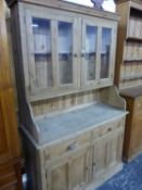 A 20th C. PINE DRESSER, THE TWIN PANELLED DOORS TO THE TOP GLAZED OVER SHELVES, THE BASE WITH