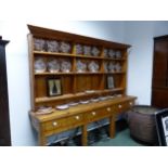 A PINE DRESSER, THE ENCLOSED BACK WITH THREE BANKS OF THREE SHELVES RECESSED ABOVE THREE DRAWERS