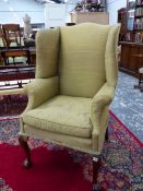 A 19th C. WING ARMCHAIR UPHOLSTERED IN OLIVE GREEN, THE CABRIOLE FRONT LEGS CARVED WITH LEAVES AT