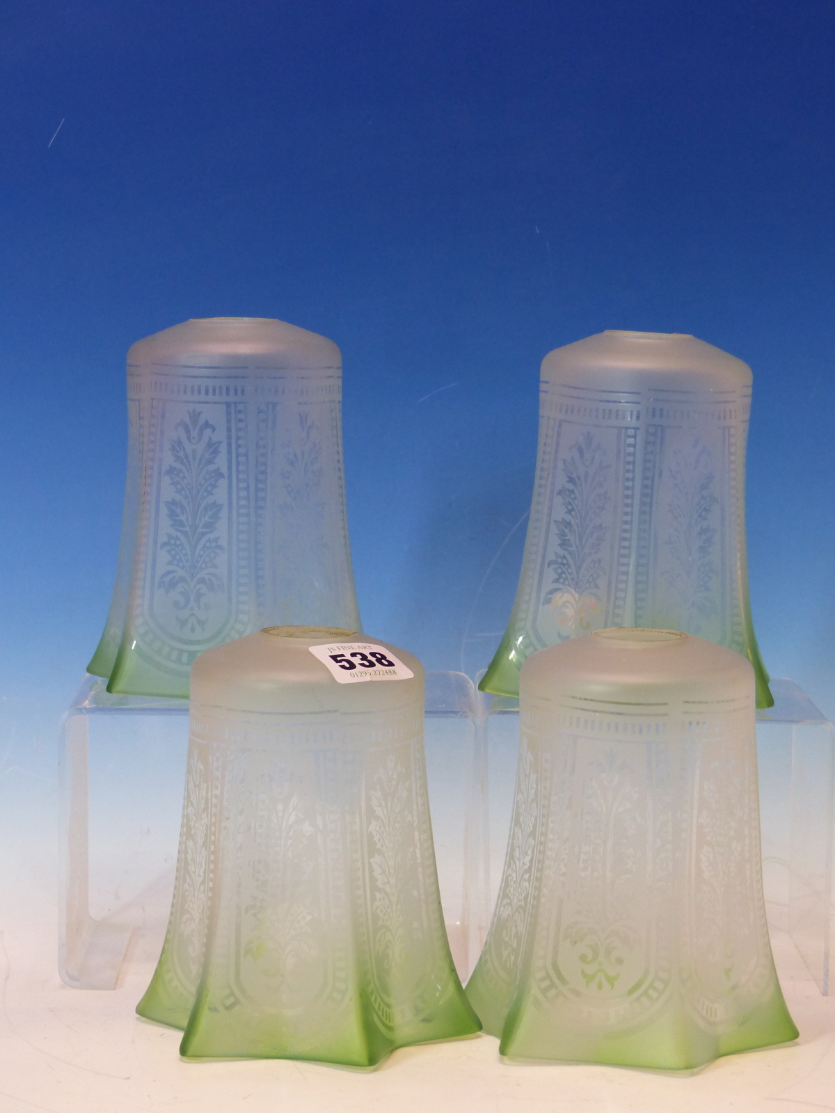 A SET OF FOUR ETCHED GLASS SHADES WITH GREEN TINTED HEXAFOIL RIMS. H 14cms.