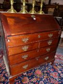 A GEORGE III MAHOGANY BUREAU, THE FALL OPENING ONTO PIGEON HOLES, DRAWERS AND A SLIDE CONCEALED