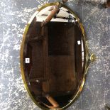 A LARGE OVAL BRASS FRAMED MIRROR.