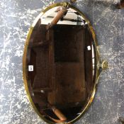 A LARGE OVAL BRASS FRAMED MIRROR.