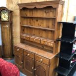 A SMALL PINE DRESSER WITH THREE DOORS AND DRAWERS AND THRE FURTHER TO THE RACK.