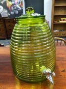 A GREEN GLASS LIDDED DISPENSING URN.