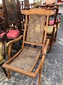 AN ANTIQUE CAMPAIGN TYPE FOLDING LOUNGER WITH CANE BACK AND SEAT.