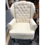 A WING BACK ARM CHAIR ON CABRIOLE FORE LEGS.