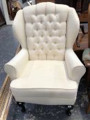 A WING BACK ARM CHAIR ON CABRIOLE FORE LEGS.