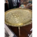 A BRASS DISH WORKED WITH FRUITING VINES AND SUPPORTED ON A FOLDING BASE TOGETHER WITH A CANED BACK