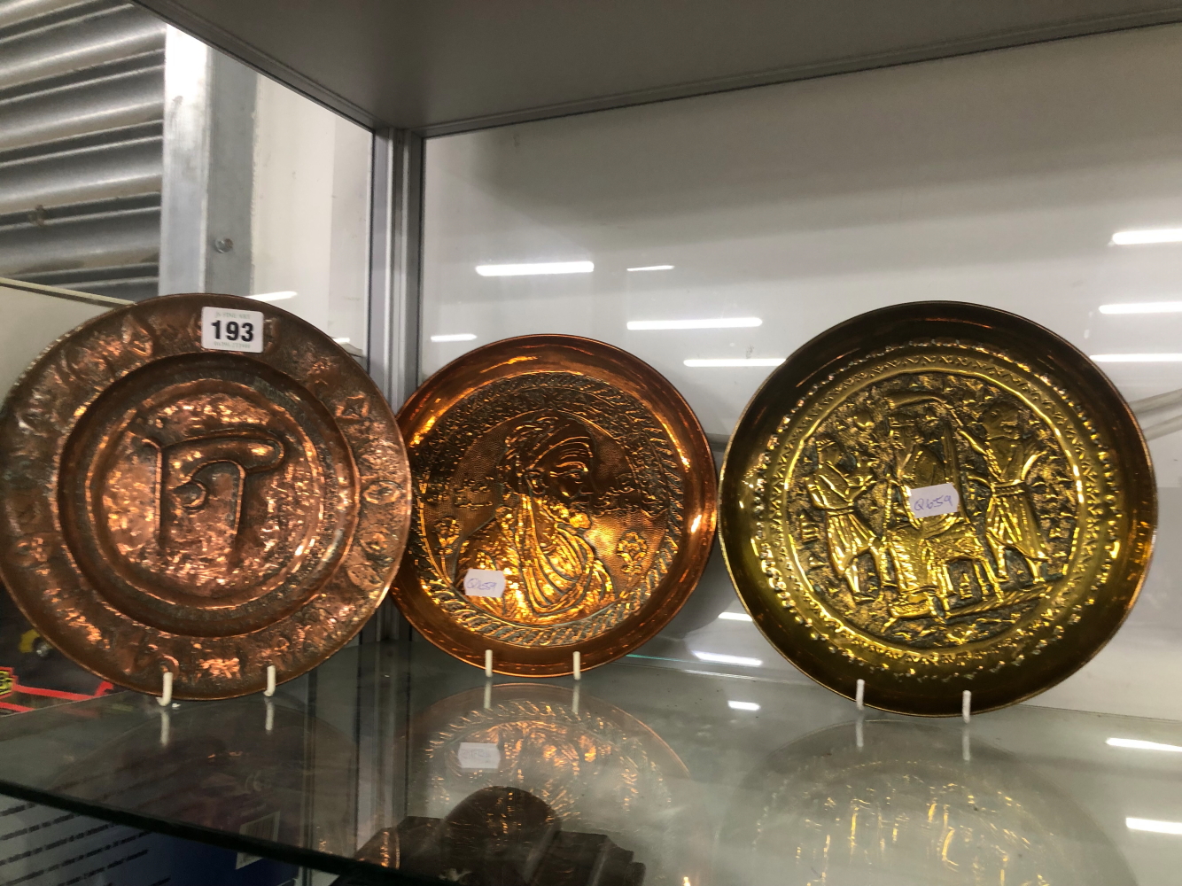 THREE MIDDLE EASTERN REPOUSSE DECORATED METAL DISHES.