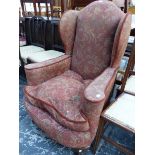 A 20th C. WING ARMCHAIR, THE UPHOLSTERY WITH A PLUM GROUND COLOUR, THE FRONT BALL AND CLAW FEET IN