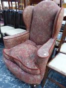 A 20th C. WING ARMCHAIR, THE UPHOLSTERY WITH A PLUM GROUND COLOUR, THE FRONT BALL AND CLAW FEET IN