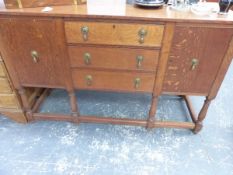 A 20th C. OAK SIDEBOARD WITH THE CENTRAL THREE DRAWERS FLANKED BY CUPBOARDS, THE FOUR BALUSTER FRONT