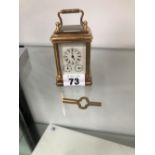A MINIATURE BRASS CASED CARRIAGE CLOCK WITH TRIPLE DIAL.