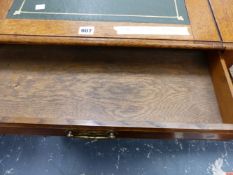 AN EDWARDIAN OAK DESK, THE LEATHER INSET TOP SLIDING OUT OVER A DRAWER, THE SQUARE LEGS TAPERING