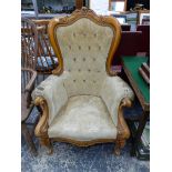 A VICTORIAN STYLE BEECH SHOW FRAME ARMCHAIR THE S-SCROLL BACK CENTRED BY A FLOWER ABOVE BUTTONED BEI