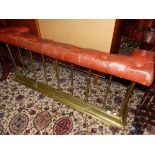 AN ANTIQUE BRASS AND LEATHER UPHOLSTERED CLUB FENDER.