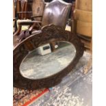 AN EDWARDIAN OVAL MIRROR WITHIN A MAHOGANY FRAME CARVED WITH ENTRELAC. 108 x 74cms.