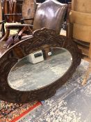 AN EDWARDIAN OVAL MIRROR WITHIN A MAHOGANY FRAME CARVED WITH ENTRELAC. 108 x 74cms.