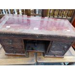 AN ORIENTAL MINIATURE PEDESTAL CABINET, THE CENTRAL NICHE FLANKED BY THREE AND A DOOR EACH CARVED IN