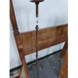 AN IRON FLOOR STANDING CANDLESTICK, THE COLUMN CAST WITH KNOPS AND BALUSTERS ABOVE THE TRIPOD. H