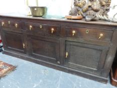 A 19th C. OAK DRESSER, THE THREE DRAWERS OVER TWO DOORS FLANKING A CENTRAL PANEL ABOVE THE PLINTH