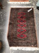 AN ORIENTAL RUG OF BOKHARA DESIGN. 131 x 79cms. TOGETHER WITH A MACHINE MADE RUG OF SIMILAR