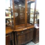 A 20th C. MAHOGANY CABINET, THE UPPER HALF WITH GLAZED DOORS OVER SHELVING, THE BOWED FRONT BASE WIT