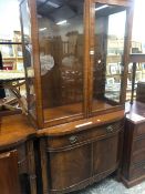 A 20th C. MAHOGANY CABINET, THE UPPER HALF WITH GLAZED DOORS OVER SHELVING, THE BOWED FRONT BASE WIT