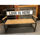A WOODEN SEATED IRON GARDEN BENCH, THE WHITE BACK BAR INSCRIBED IN BLACK LOVE IS HERE. W 123cms.