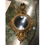 A ANTIQUE CIRCULAR CONVEX MIRROR IN A GILT ROCOCO FRAME CARVED WITH FLOWERS AND ROCAILLE. 63 x 37cms