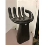 AN EBONISED WOODEN STOOL CARVED IN THE SHAPE OF AN OPEN HAND AND FOREARM. W 40 x D 41 x H 69cms.