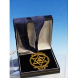 A GILT METAL MASONIC PENDANT BY THOMAS HARPER, THE INSCRIBED STAR OF DAVID WITHIN A RIBBON TIED