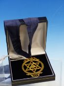 A GILT METAL MASONIC PENDANT BY THOMAS HARPER, THE INSCRIBED STAR OF DAVID WITHIN A RIBBON TIED