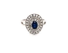 A SAPPHIRE AND DIAMOND HALO CLUSTER RING. THE OVAL CUT SAPPHIRE IN A FOUR CLAW RAISED SETTING,