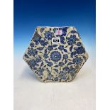 AN EARLY HEXAGONAL IZNIK TILE DECORATED IN BLUE, TURQUOISE AND BLACK WITH VINES FLOWERING