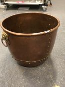 A COPPER LOG BASKET APPLIED WITH BRASS LION MASK AND RING HANDLES. Dia. 55 x H 45cms.