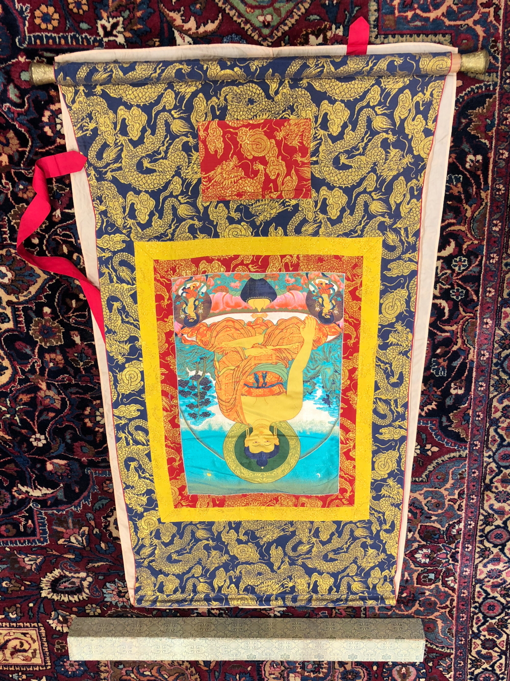 A SINO-TIBETAN MACHINE WOVEN SILK SCROLL DEPICTING THE BUDDHA SEATED CROSS LEGGED ON A LOTUS THRONE.