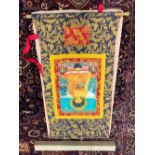 A SINO-TIBETAN MACHINE WOVEN SILK SCROLL DEPICTING THE BUDDHA SEATED CROSS LEGGED ON A LOTUS THRONE.