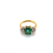 AN 18ct YELLOW GOLD HALLMARKED EMERALD AND DIAMOND RING. THE RECTANGLE CUT EMERALD APPROX