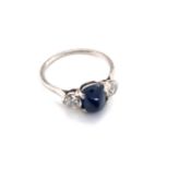 A VINTAGE SUGARLOAF CABOCHON SAPPHIRE AND OLD CUSHION CUT DIAMOND TRILOGY RING. THE CENTRAL