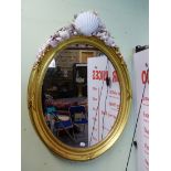 A PAIR OF OVAL MIRRORS, THE BEADED AND RIBBON TIED GILT FRAMES NOW SURMOUNTED BY ARRANGEMENTS OF